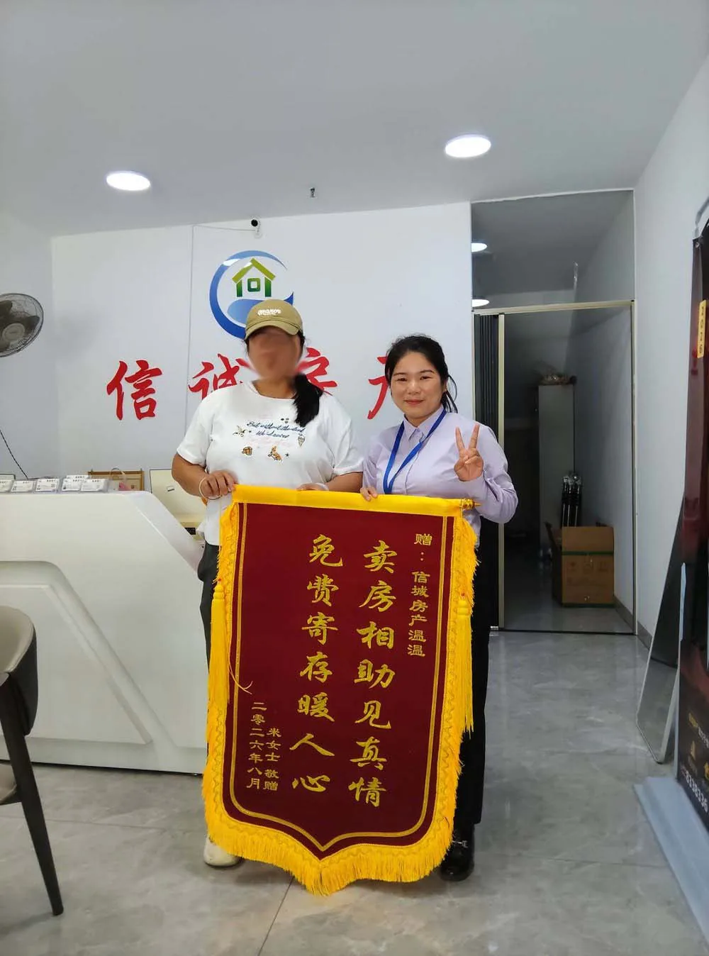 2026 年 8 月，买方米女士向浦北县信诚房地产中介有限公司（浦北信诚房产）经纪人温温赠送锦旗的门店合影，锦旗上书「卖房相助见真情 免费寄存暖人心」
